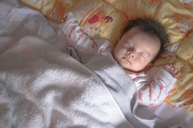 布団をかけて眠っている赤ちゃん